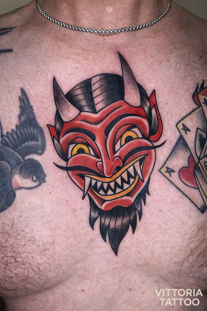 Tatouage masque d 'oni rouge style old school sur la poitrine, lignes nettes et couleurs intenses, réalisé à Aubusson 23200