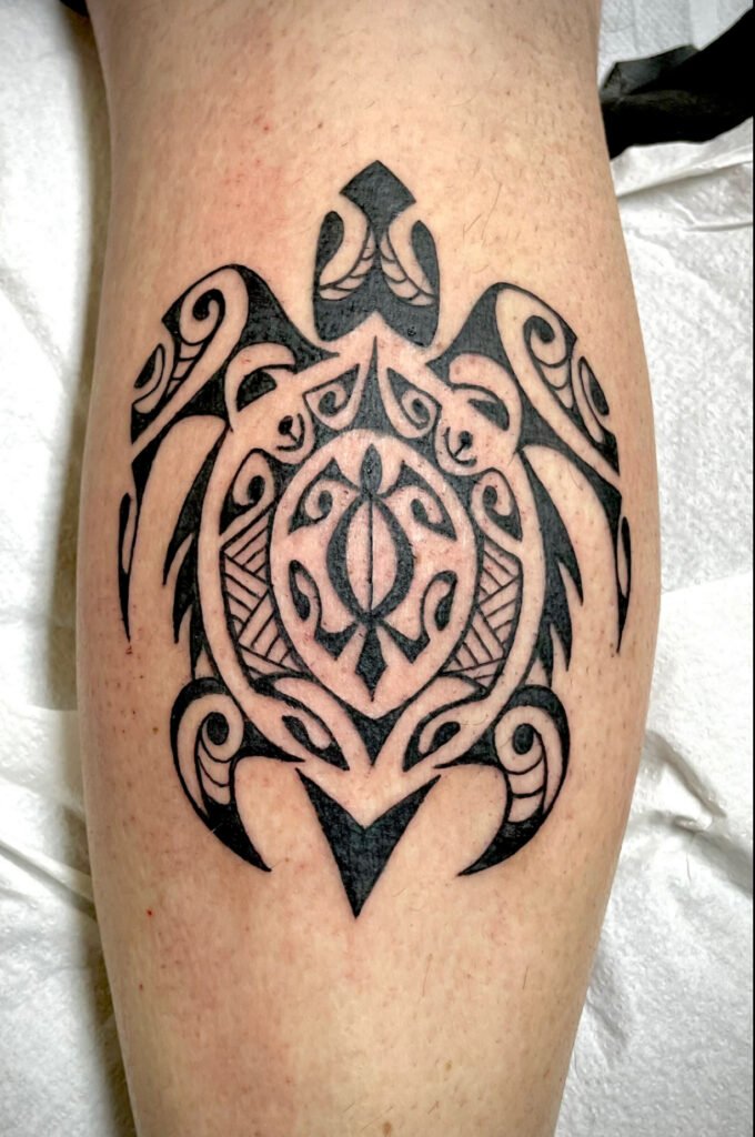 Tatouage tortue style maori noir avec motifs polynésiens réalisé sur mollet
