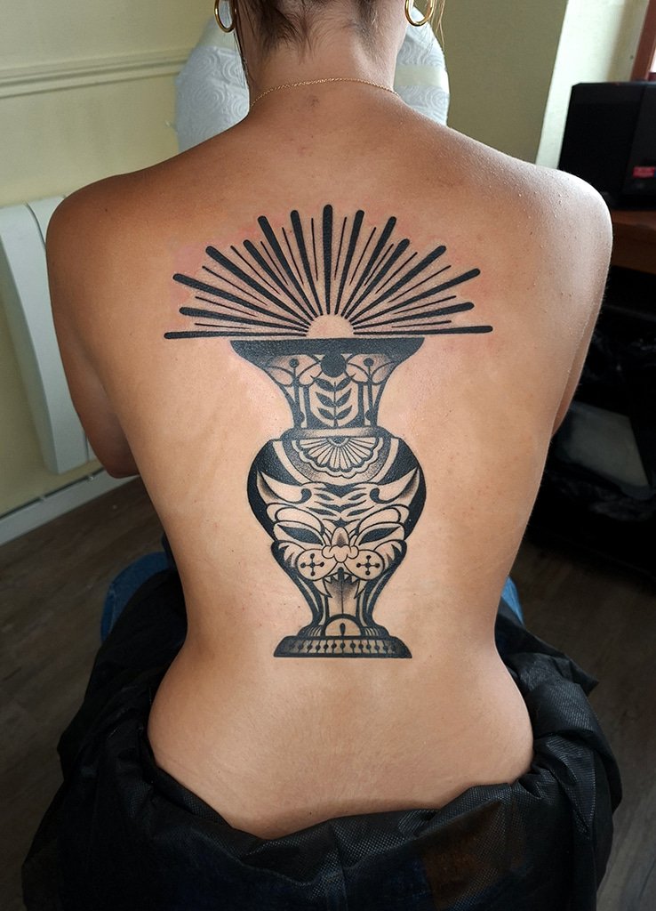 Tatouage vase Old School stylisé en noir sur le dos avec rayons graphiques, réalisé par Vittoria Tattoo