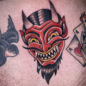 Tatouage masque d 'oni rouge style old school sur la poitrine, lignes nettes et couleurs intenses, réalisé à Aubusson 23200