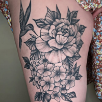 Tatouage pivoine fleurs et colibri noir et gris sur la cuisse.