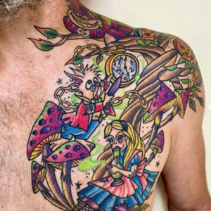 Tatouage coloré inspiré d’Alice au pays des merveilles avec personnages et champignons sur l’épaule et le torse, réalisé à Aubusson par Vittoria Tattoo.